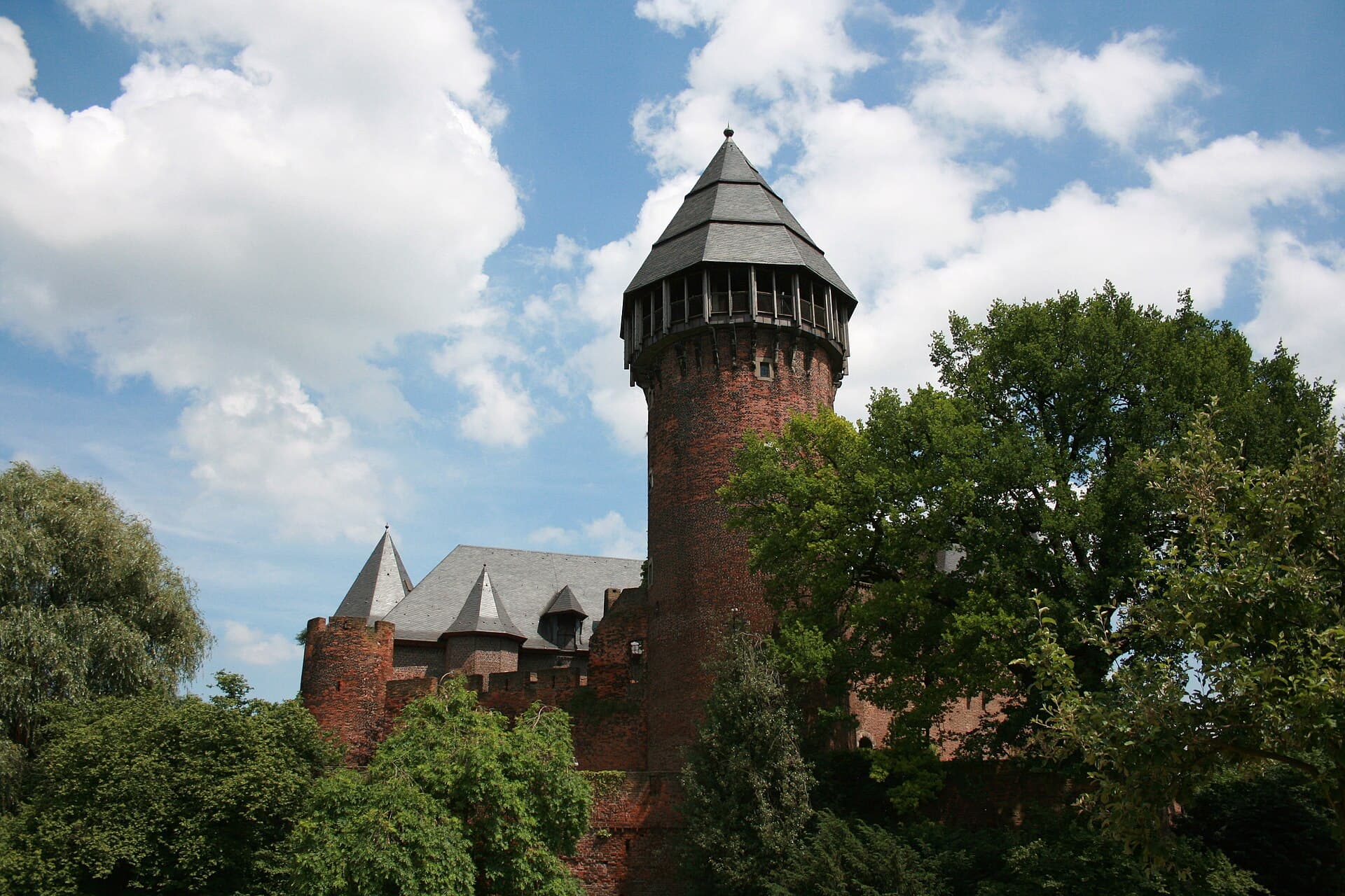 Die mittelalterliche Wasserburg Burg Linn in Krefeld mit Bergfried und Ringmauer, umgeben von ihrem Wassergraben – das Wahrzeichen des Stadtteils Linn.